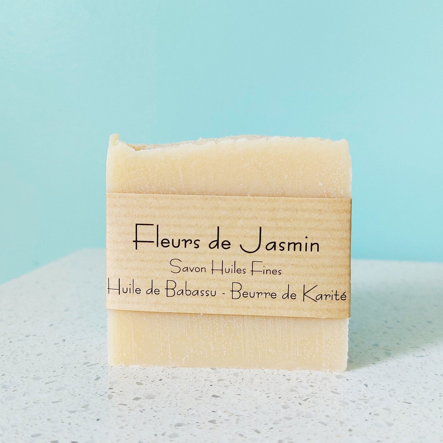 Savon jaune pâle avec parfum de fleurs de jasmin, sur une plateau en marbre blanche et arrière-plan bleu tourquoise, ILELI savonnerie