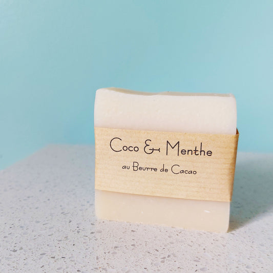 Pain de savon coco et menthe avec banderole en papier kraft devant une arrière-plan bleu