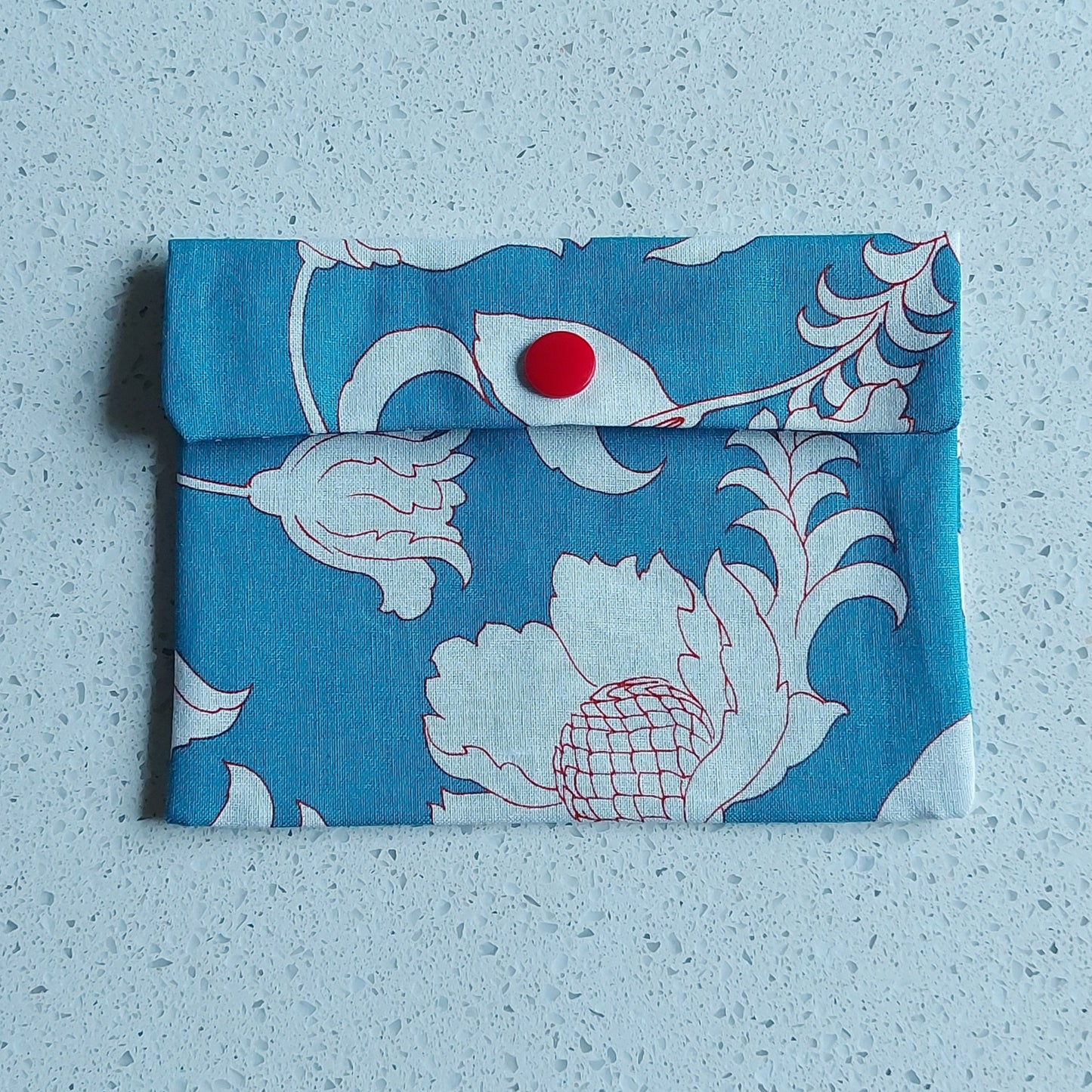 Pochette à savon, model 'Copenhague', bleu clair avec illustration fleurs blanches et rouges, doublure en coton enduit bleu foncé à piis blanches, ILELI savonnerie Igny