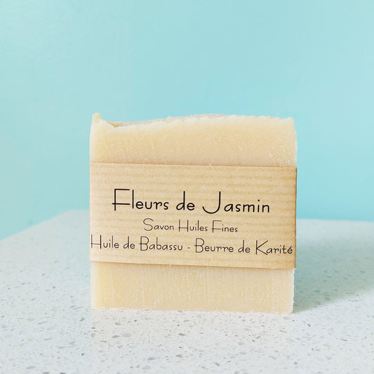 Savon jaune pâle avec parfum de fleurs de jasmin, sur une plateau en marbre blanche et arrière-plan bleu tourquoise, ILELI savonnerie