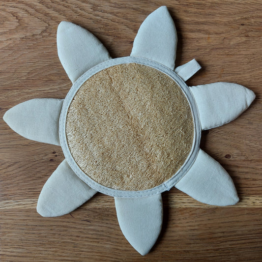Une jolie éponge de luffa en forme de soleil ou de fleur est posée sur une table en bois. C'est le jouet de bain idéal pour les petits enfants. Salle de bain zéro déchet - gant de massage naturel et bio-dégradable. Produit de ILELI savons Orsay